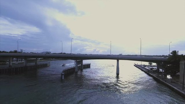 Aerial pan of bridge in Miami with boat passing by 