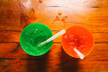 two plastic glass with straw on wooden background