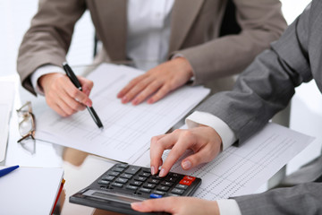 Fototapeta premium Two female accountants counting on calculator income for tax form completion hands closeup. Internal Revenue Service inspector checking financial document. Planning budget, audit concept