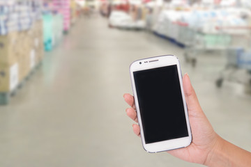 Hand woman holding smartphone on supermarket background.