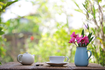 Flowers with blue vintage pot and tea set on wooden table