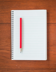 Note book with a red pencil on wood table