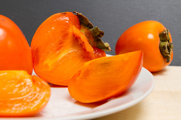Cut a ripe persimmon on a white plate