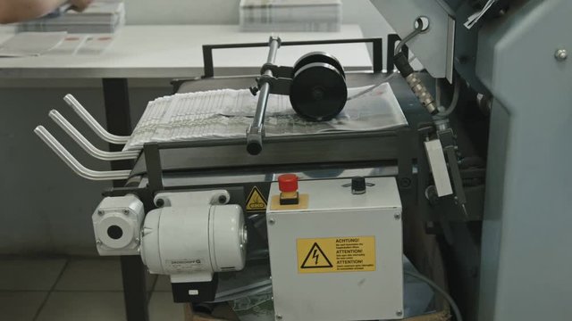 Printing Process on polygraph industry - female hands collect brochures from the conveyor belt