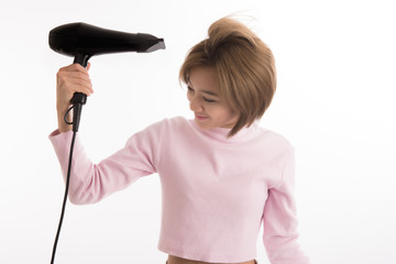 Asian woman uses hair dryer on white background.