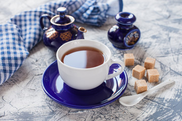 tea in a cup, a teapot and sugar on a table, selective focus