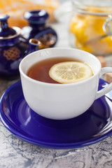 tea with a lemon in a cup, a teapot and sugar on a table, selective focus