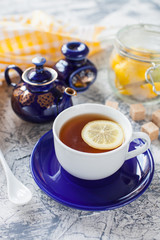 tea with a lemon in a cup, a teapot and sugar on a table, selective focus