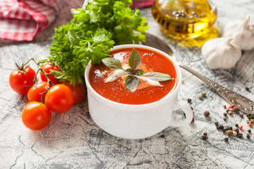 tomato soup with a basil in a bowl on a table, selective focus