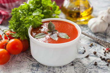tomato soup with a basil in a bowl on a table, selective focus