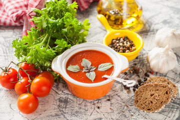 tomato soup with a basil in a bowl on a table, selective focus