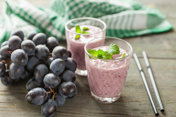 milkshake with banana and grapes in a glass on a table, selective focus