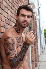 Sporty handsome shirtless tattooed man holding a cigarette