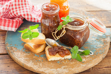 strawberry jam, a fig and apricots in jars on a table, selective focus
