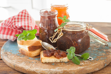strawberry jam, a fig and apricots in jars on a table, selective focus