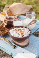 cottage cheese, coffee, jam, milk and bread on a bench in a garden, selective focus