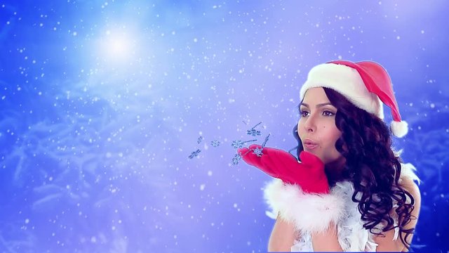 Girl in Christmas hat blowing flying snowflake on blue snow background. Group of flying snowflakes on clear blue winter sky.