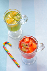 Cold red, green liquors and lollipop on blue background