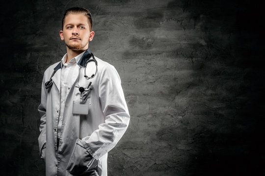 Portrait of confident young medical doctor on grey background.