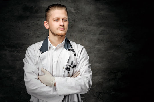 Portrait of confident young medical doctor on grey background.