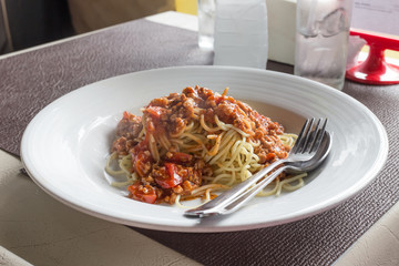 Spaghetti with pork tomato sauce in white dish on table