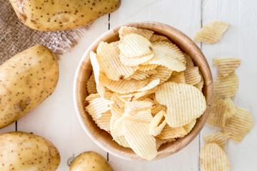 Crispy potato chips in a wooden bowl on wooden table