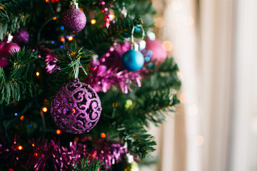 Closeup of bauble hanging from a decorated Christmas tree. 