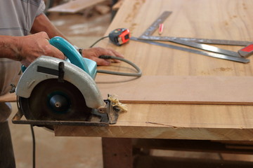 Hand of worker cutting wood with electric circle saw