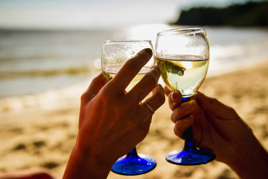 Young couple drinking wine on the beach.