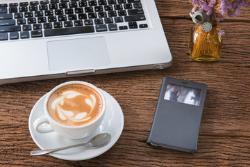 Heart drawing on latte art  coffee cup and notebook and smartphone.