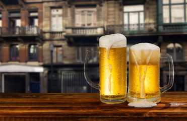 cold mug of beer with foam on the background of the street