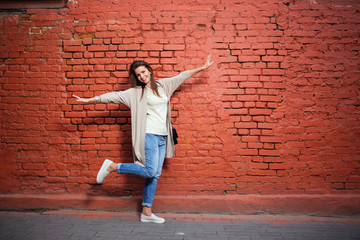 Fototapeta na wymiar Young beautiful happy woman in casual cloths against brick wall