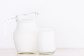 Obraz na płótnie Canvas Glass jug and glass with milk on wooden table