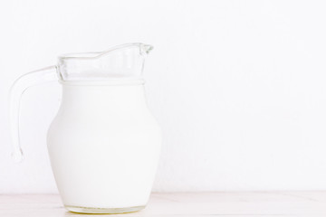 Glass jug with milk on wooden table
