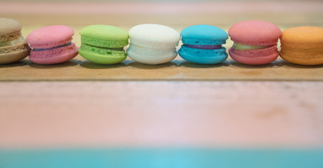Multicolored macaroons on white wooden background. . Macaron or Macaroon is sweet meringue-based confection