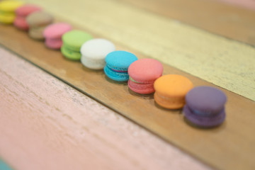 Obraz na płótnie Canvas Multicolored macaroons on white wooden background. . Macaron or Macaroon is sweet meringue-based confection
