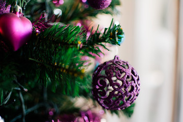Closeup of bauble hanging from a decorated Christmas tree.
