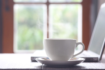 Notebook and cup of coffee on the old wooden table. Simple workspace or in the morning Coffee Break / selected focus.
