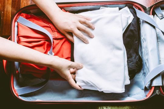 Woman's hands packing a luggage
