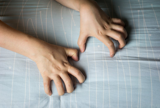 Woman hand grasping on bed sheet