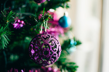 Closeup of bauble hanging from a decorated Christmas tree.