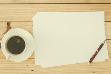 Blank paper page and cup coffee  with pen on wooden table
