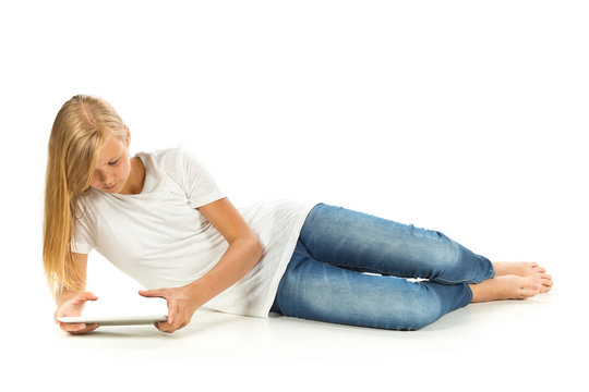 Young girl lying on the floor using tablet pc over white backgro
