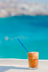 Frappe, ice coffee on the beach. Summer iced coffee frappuccino, frappe or latte in a tall glass background the sea in beach bar
