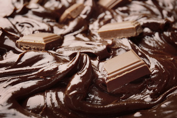 Delicious melted chocolate with pieces, closeup