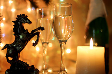 Dark yellow Style New Years Eve celebration background with horse an elegant arrangement with a clock counting down to midnight, flutes and bottle of champagne and party streamers with a candles.