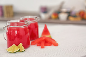 Jars with smoothie, watermelon and lime slices on kitchen table