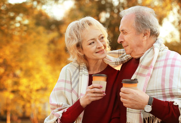 Lovely mature couple with coffee in autumn park