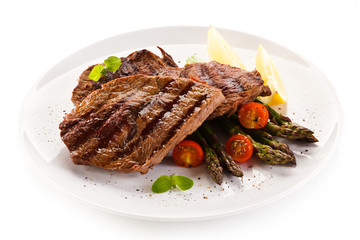 Grilled beef steaks and asparagus on white background 