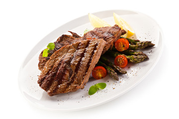 Grilled beef steaks and asparagus on white background 